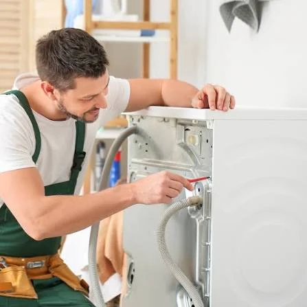 Technician checking connections at the back of a laundry appliance