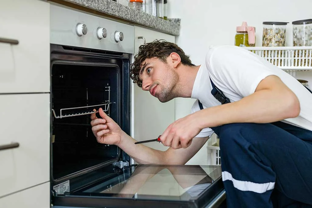 Appliance technician inspecting the inside of an open kitchen oven