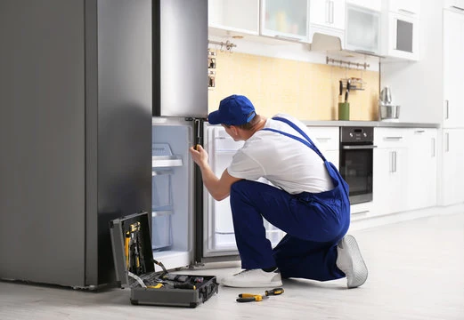 Technician inspecting the freezer compartment of a refrigerator with tools nearby